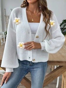 White chunky knit cardigan featuring 3D floral patches and marble pattern buttons
