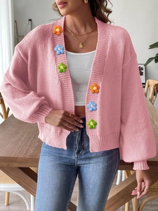 Close-up of colorful 3D knitted flower embellishments on a pink open-front cardigan