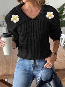 Detail of black knit sweater with 3D white crochet flower appliques on shoulders