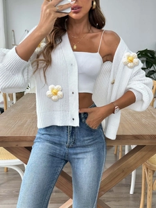 Close-up of 3D crochet daisy appliques on a white chunky knit cardigan sweater