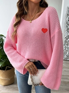 Detail of pink hollow knit sweater featuring a red heart embroidery and wide neckline