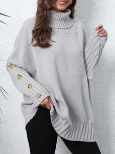 Detailed view of light grey knit sweater featuring turtleneck and amber buttons on sleeves