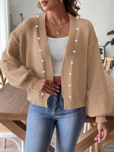 Detailed macro view of khaki knit cardigan featuring elegant pearl button embellishments
