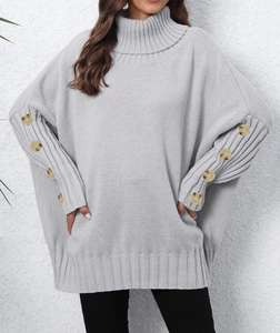 Detail of grey oversized high neck knit sweater featuring amber-toned button sleeve accents