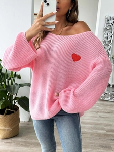 Close-up of pink oversized knit sweater with a red heart embroidery patch and soft texture