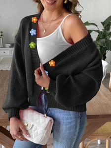 Women's black chunky knit cardigan with colorful crochet floral patches and lantern sleeves