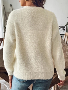 Dettaglio del cardigan in finta pelliccia color crema con texture soffice e bordo a coste