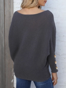 Detail of dark gray knit sweater cuffs featuring elegant pearl buttons and gold trim