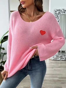 Detail of soft pink knit sweater showing a vibrant red heart patch on the chest area