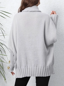 Detail of light gray oversized knit sweater with amber decorative buttons on the sleeve cuffs