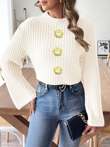 Detailed knit texture of off-white sweater with crochet flower patches and bell sleeves