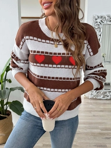 Detail of red heart embroidery and striped pattern on brown knitted long sleeve sweater