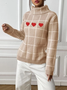 Close-up of beige plaid turtleneck sweater with red heart embroidery detail and soft knit