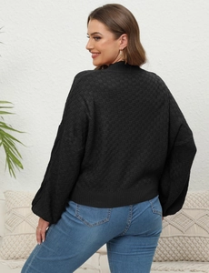 Detail of black knit sweater featuring checkered jacquard texture and lantern sleeves