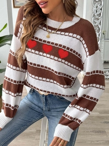 Close-up of striped knit sweater with red embroidered heart patches and detailed stitching