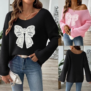 Dettaglio del maglione in maglia con scollo a barca e toppa ricamata con fiocco in pizzo