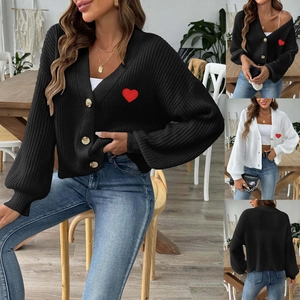 Dettaglio del cardigan in maglia con scollo a V, bottoni e ricami a cuore rosso