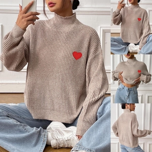 Detail view of beige knit sweater with red heart patch and ribbed mock neck finish