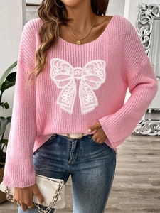 Dettaglio della maglia rosa con patch a fiocco in pizzo bianco e trama a treccia