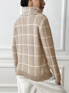 Detail of high turtleneck sweater featuring large white check pattern and ribbed cuffs