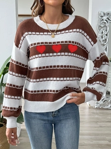 Close-up of red heart embroidery on striped sweater with detailed knit texture
