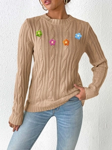 Close-up of khaki knit sweater with colorful crochet flower patterns and ribbed cuffs