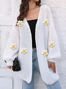 Detail of chunky knit white cardigan featuring 3D handmade crochet daisy floral patterns