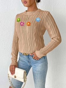 Detail of khaki cable knit sweater featuring colorful 3D handmade crochet flower patches