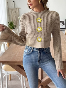 Close-up of knit cropped sweater featuring 3D floral appliques and flared sleeves