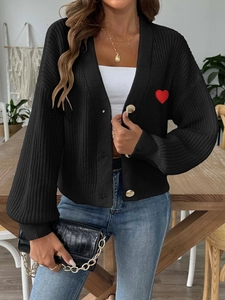 Dettaglio del ricamo a cuore rosso su cardigan nero in maglia con bottoni singoli
