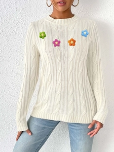 Detail of cable knit texture on women's white sweater with colorful crochet flowers