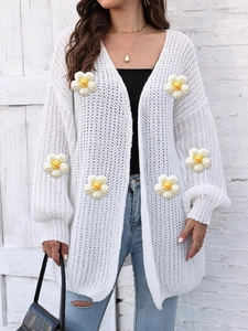Detail of white chunky knit cardigan with yellow and white 3D crochet flower appliques