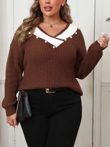 Close-up of V-neck patchwork knit sweater with elegant pearl bead accents and textures