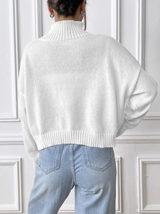 Rear view of a white turtleneck knit sweater featuring ribbed cuffs and hem detail