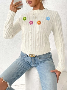 Detail of colorful handmade crochet floral appliques on cream knitted crewneck sweater