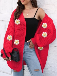 Close-up of chunky knit red cardigan featuring 3D floral appliques and soft texture