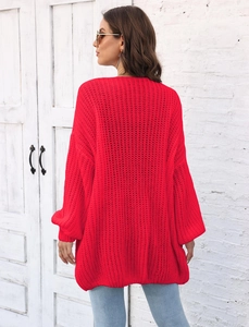 Detail of red chunky knit cardigan featuring drop shoulder design and ribbed texture weave