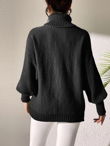Back view of a black oversized turtleneck knit sweater showing ribbed cuffs and texture