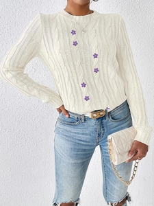 Detailed cable knit pattern on off-white sweater with delicate floral embroidery