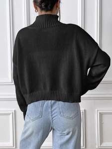 Detail view of the back of a black high-neck knit sweater with heart patches and loose fit