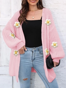 Close-up of pink chunky knit cardigan featuring 3D white daisy floral appliques