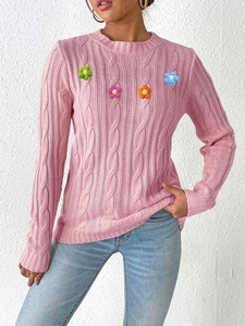 Detail of pink knit sweater with colorful 3D crochet flower appliques on the chest