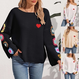 Detail of colorful crochet flowers on sleeves of an off-shoulder knitted sweater top