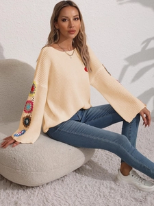 Detail of loose knit beige sweater with colorful floral crochet patches on sleeves
