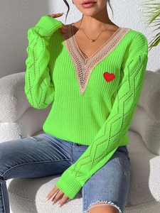 Détail du pull en maille vert fluo col en V avec dentelle et patch cœur rouge