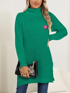 Close-up of green knit dress featuring pink flower applique and thick wool texture