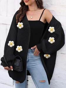 Detail of chunky knit black cardigan with 3D white daisy floral appliques and textures
