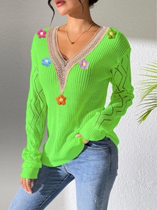 Detail of neon green knit sweater with crochet 3D flowers and lace V-neckline