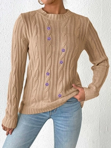 Detail of cable-knit texture and purple flower embroidery on a beige sweater