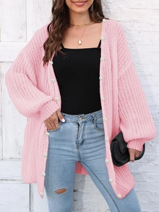 Detail of soft pink chunky knit cardigan featuring elegant white faux pearl buttons